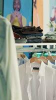 Vertikale Video leeren Kleidung Geschäft im Einkaufszentrum mit schnell Mode Kleider folgenden das neueste Tendenzen. Sortiment von elegant Männer Hemden, Hose und Gürtel im modern sauber Mode Boutique warten