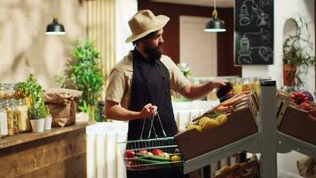 propietario reposición local barrio tienda de comestibles tienda con recién cosechado vegetales desde su propio jardín. cero residuos eco simpático Tienda empresario rellenado estantería con orgánico Produce video