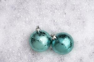 Teal Colored Christmas Ornaments Rest in the Snow Outside photo