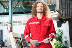 Cheerful the mechanic man in repair garage, Technician man working in auto repair shop, Car repair and maintenance concepts photo