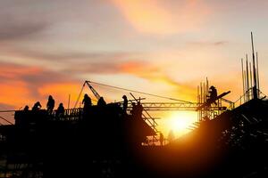 silueta de ingeniero y trabajador revisando el proyecto en el fondo del sitio de construcción, sitio de construcción al atardecer en el tiempo de la tarde foto