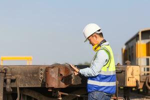 ingeniero hombre trabajando en carga tren plataforma, técnico comprobación el carga auto, profesional técnico pre chequeo carga trenes, la seguridad conceptos foto