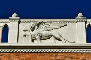 a statue of a griffin on a building against a blue sky photo