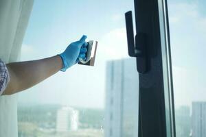 person hand in gloves cleaning window glass photo