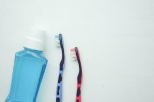 mouthwash liquid in a container and tooth brush on table photo