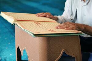 muslim man hand holding Holy book Quran at mosque photo