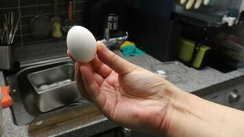 Photo of a human hand holding a boiled egg