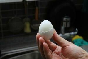 Photo of a human hand holding a boiled egg
