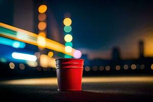 a red cup sitting on the ground in front of a city. AI-Generated photo