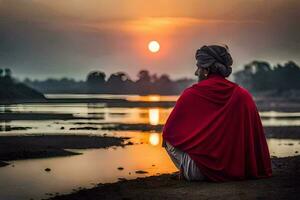 a man in a red robe sitting on the shore watching the sun set. AI-Generated photo