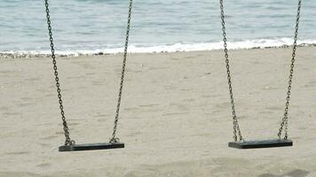 Detail of two empty seats swings in a beach video