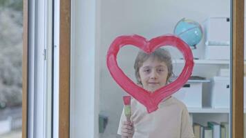 un niño pintura un corazón en un ventana vaso video