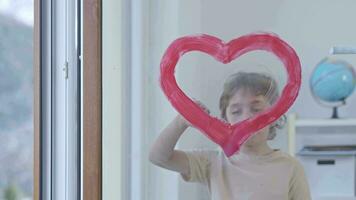 a child painting a heart on a window glass video