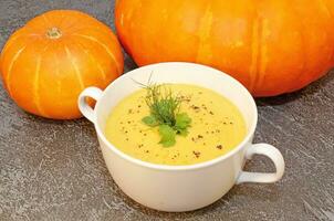 Pumpkin hot puree soup on a wooden table photo