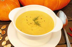 Pumpkin hot puree soup on a wooden table photo