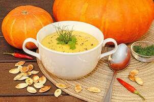 Pumpkin hot puree soup on a wooden table photo