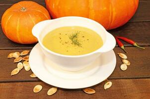 Pumpkin hot puree soup on a wooden table photo