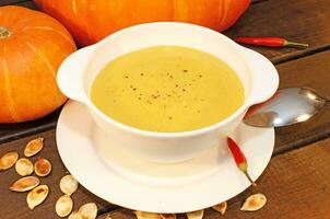 Pumpkin hot puree soup on a wooden table photo