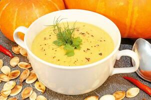 Pumpkin hot puree soup on a wooden table photo