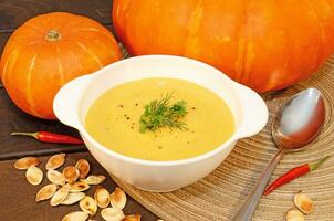 Pumpkin hot puree soup on a wooden table photo