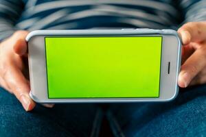 Close-up of woman holding and showing mobile phone with blank screen mockup photo