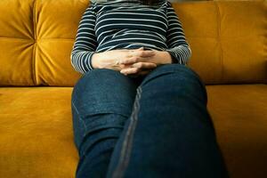 woman sits on the sofa with her legs stretched forward and her fingers crossed photo