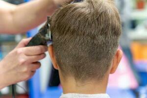 pelo corte para un niño utilizando un pelo clíper en un belleza salón foto