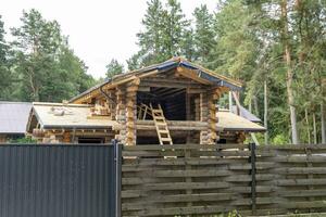 construction of a wooden log house from rounded logs in a cottage village photo