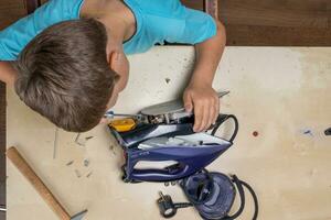 boy helps his mother. a funny master repairs an electric iron photo