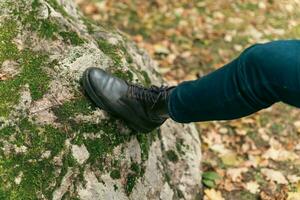 women's feet in leather autumn boots and jeans stand on the green forest moss photo