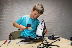 boy helps his mother. a funny master repairs an electric iron photo