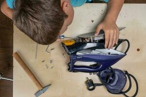 boy helps his mother. a funny master repairs an electric iron photo