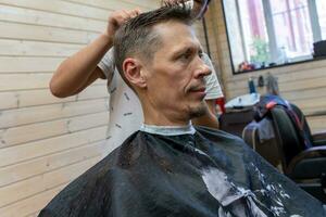 profesional peluquero cortes un del hombre cabello. visitar a el Barbero tienda foto
