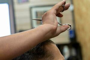 profesional peluquero cortes un del hombre cabello. visitar a el Barbero tienda foto