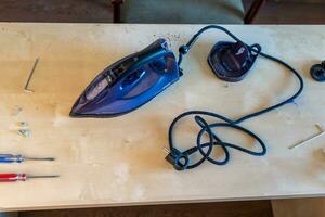 Disassembled electric iron. repairman checking and fixing broken iron photo