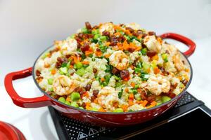 Stir fry rice with vegetables and shrimps in Red iron pan. Slate background. Top view. photo