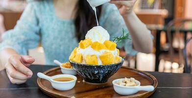 Shaved ice dessert with mango slices. Served with vanilla ice cream and whipped cream. Sweet dessert in Korean style. Local name, Bingsu. photo