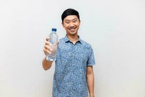 positivo asiático hombre azul camisa sostener botella de agua contento sonrisa aislado foto