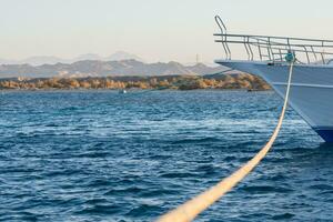 long rope from the attachment to a white boat at the sea photo