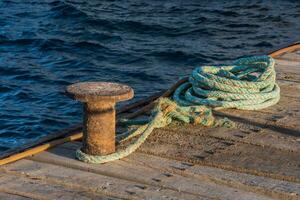 antiguo vistoso cuerda con un adjunto archivo a un embarcadero en el mar foto