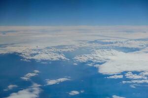 view to soft little white clouds and a blue sky during a flight photo