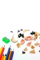 sacapuntas y juego de lápices de colores con fondo blanco de virutas de madera. foto