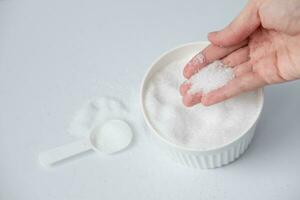 Epsom salt in hand for bath on white background. Useful salt for relaxation in the bath. Magnesium salt photo