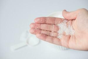 Epsom salt in hand for bath on white background. Useful salt for relaxation in the bath. Magnesium salt photo