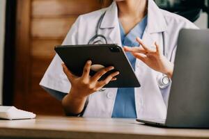 Medical doctor or physician consulting patient's health online using internet mobile digital tablet in clinic or hospital office for professional emergency healthcare assistance service concept photo