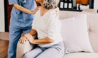 Happy young female nurse provide care medical service help support smiling old grandma at homecare medical visit, lady carer doctor give empathy encourage retired patient sit on sofa at home hospital photo