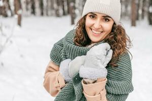 A cute girl with a green scarf in mittens stands in the snow in winter photo