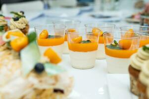 Candy bar for the holiday with muffin and cream, tangerine panna kota , desserts on the table photo