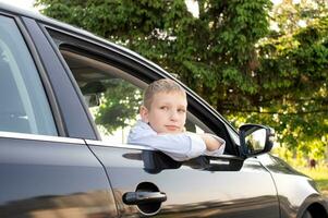 A cute boy looks out the car window and is sad. Open car window photo