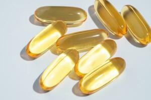 Fish Oil Omega 3 on white background, vitamin D yellow supplement gel capsules, macro shot photo